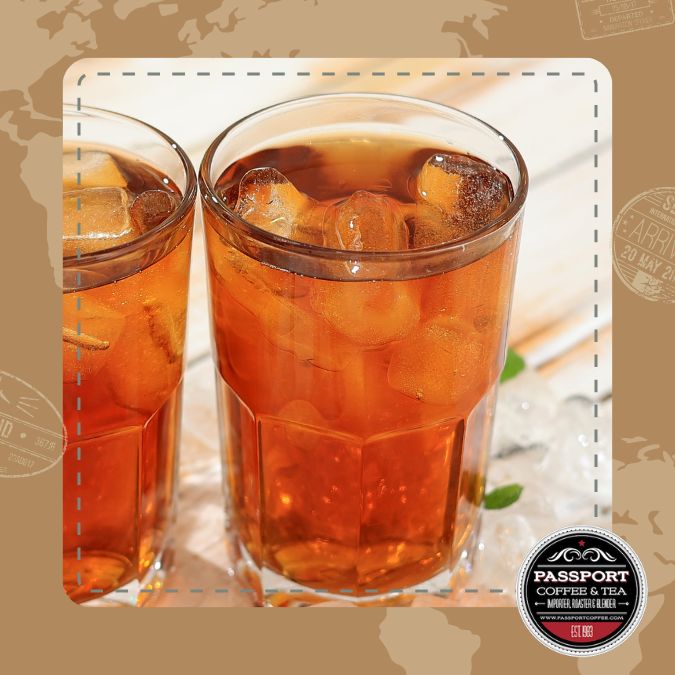 Tropical Black Iced Tea in glass with ice cubes, infused with passion fruit and pineapple.