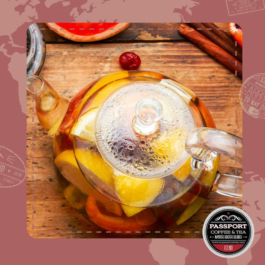 Mandarin Orange Fruit and Spice Tea in glass teapot with orange slices and spices.