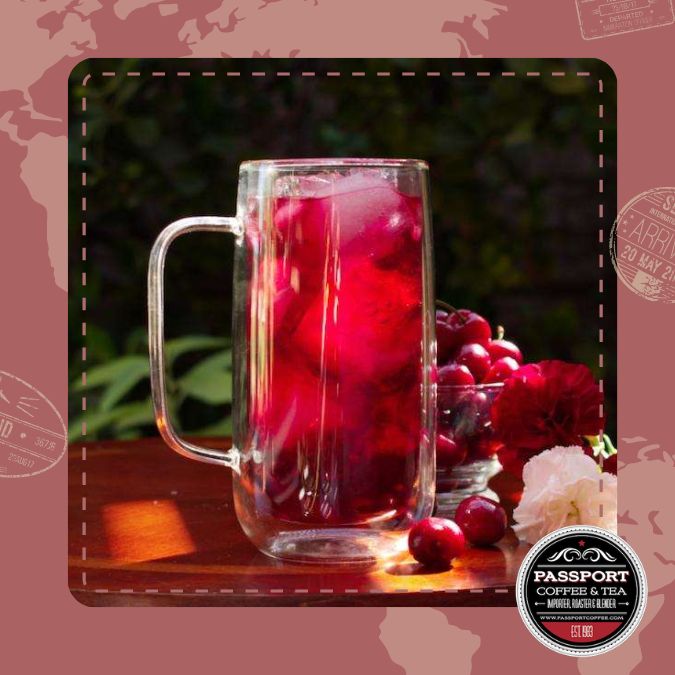 Berry fruit tea with cranberries, hibiscus, and elderberries in a clear mug on a wooden surface.