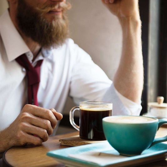 Man enjoying a cup of Decaf Forster and Burnett Blend coffee at a cafe.