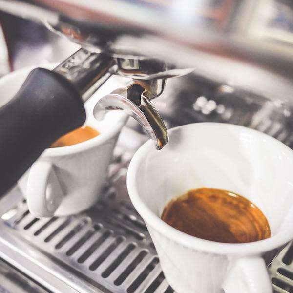 Milano Espresso brewing into white cups with rich caramel crema.